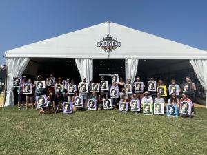 Large white  tent with Rockstar Art Class printed on it and several people standing out front showing off their artwork.