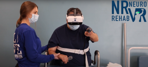 Image contains a person on the left wearing a mask and holding the arm of a person on the right wearing a VR headset reaching out with their left hand