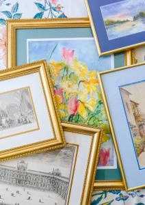 An assortment of custom picture frames including colorful matting and ornate gold frames