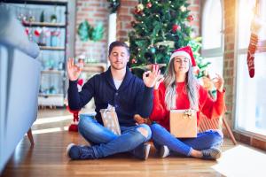 a couple making yoga next to Christmas Tree to remove stress from holidays