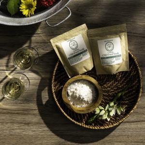 Life Elements Inspired Sip & Foot Soak Experiences features a galvanized tup filled with water and flowers next to two glasses of wine and a basket of Cooling CBD Foot Soaks.