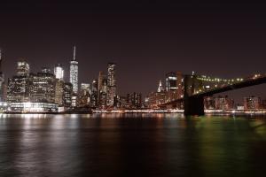 The Brooklyn bridge at night with the city in the background.