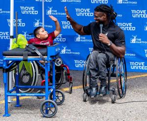 Matt Scott high fiving a younger athlete in a wheelchair