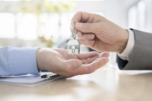 Holding house keys on house shaped keychain concept for buying a new home