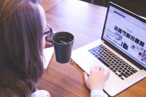 Woman working on laptop holding a cup of tea
