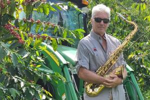Steve Wynn on Kona Earth coffee farm holding his saxophone