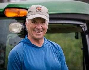 Steve Wynn stands in front of tractor on the farm