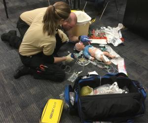 EMTs practicing providing medical services to a dummy child