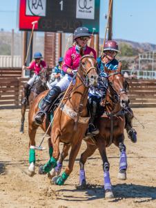 Two opponents in the USPA Women's Arena Open riding polo horses in a defensive play during an arena polo match