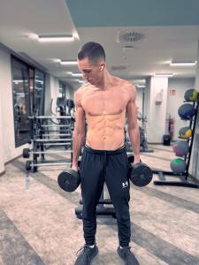A sportsman lifting dumbbells at home topless