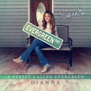 A picture of Dianña sitting in a chair on a porch holding an Evergreen street sign