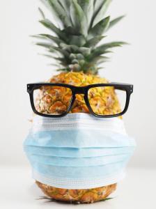 Pineapple wearing a surgical mask and sunglasses