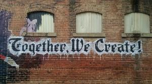 A wall with graffiti that says "Together We Create"