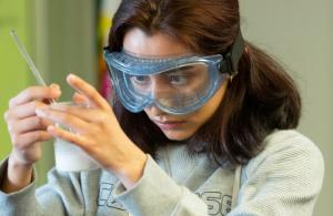 A student looks at a solution in a beaker.