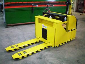 Large Yellow with black stripes around the forks of pallet truck in front of a heavy press machine with battery