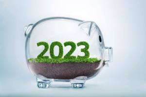 Grass growing in the shape of year 2023, inside a transparent piggy bank