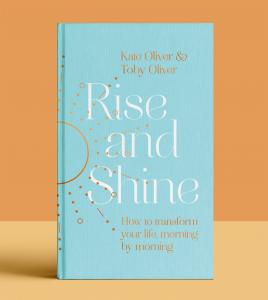 The new book 'Rise and Shine - How to transform your life, morning by morning' which features a golden sun motif on a sky blue cover against a soft orange wall