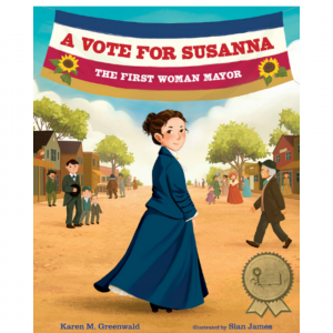 This is the cover of the nonfiction picture book, A VOTE FOR SUSANNA, THE FIRST WOMAN MAYOR. There is a woman dressed in blue looking over her shoulder at the reader. She stands in the center.  A blue, white, and red banner hangs in a swag behind her--the title in red.