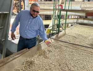 GrainChain CEO and Co-Founder, Luis Macias, reaching into a bin of dried coffee beans while visiting a coffee cooperative in Mexico.