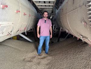 GrainChain Chief Strategy Officer, Jaime Lopez, standing in between two cylinders that are part of a machine that processes coffee, while visiting a coffee cooperative in Mexico.