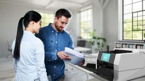 Two office workers scan documents using the InoTec SCAMAX 3x1 table top document scanner.