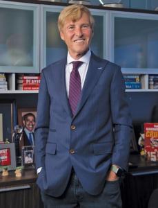 Leigh Steinberg stands for a photo in front of shelves filled with sports memorabilia.