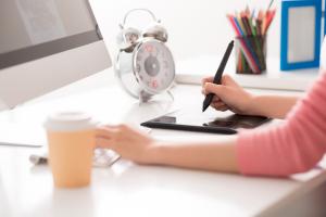 Unrecognizable woman working on a laptop, at a desk.