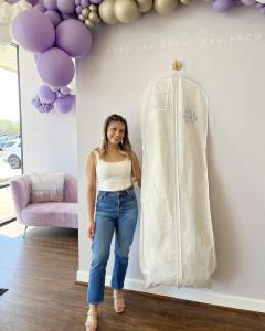 A bride posing with her garment bag at Luxe Redux Bridal Houston celebrating her yes to the dress moment