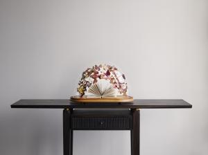 An opened book surrounded by paper butterflies enclosed in Victorian glass dome