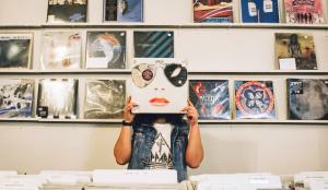 Man with vinyl in front of his face in music store
