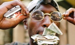 Man with glasses on with money in his mouth