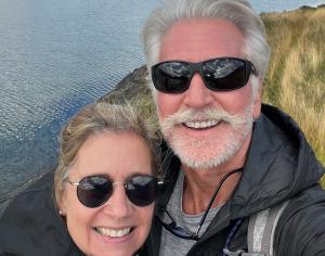 closeup photo of man and women along grassy lakeshore on partly cloudy afternoon