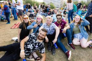 A group of friends sitting on the grass enjoying the Waterfront Blues Festival on a sunny day.