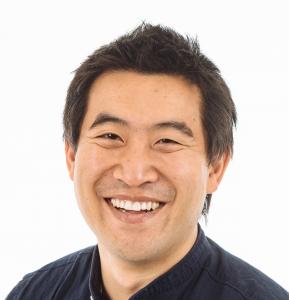 A professional headshot of Award winning Youtuber and International Marketing Icon Kwai Chi. Kwai is wearing a dark blue shirt and smiling at the camera.