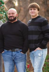 Two men standing in front of a decorative concrete coating project, celebrating their early business success as a father-son duo.