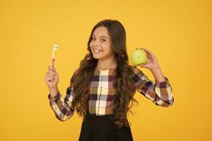 child holding apple and toothbrush