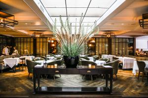 Baltaire Restaurant & Steakhouse's Interior Dining Room depicting a wine credenza and large flower arragement against white tablecloth tables with chairs and a skylight