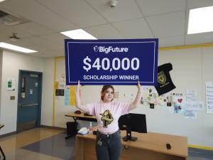 Mia holds up a giant $40,000 BigFuture college scholarship check