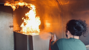 An Aircare FACTS Training student practices putting out a fire during a Fire Trainer demonstration.