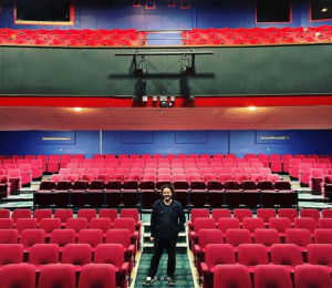 Edgar Wright stands in the middle of an auditorium seating area.
