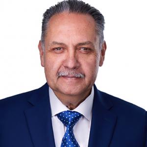 This photograph is a portrait shot of Armando Contreras in a suit. He is the president and chief executive officer of United Cerebral Palsy.