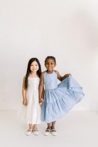 Two flower girls standing together - one in a light pink dress and the other in blue.