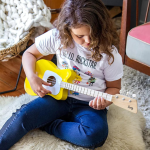 Young child plays a yellow Loog Mini acoustic guitar