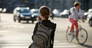 Young Woman with backpack crossing the street with traffic in the background