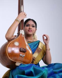 Young female singer in bright blue traditional dress with ancient wooden musical instrument