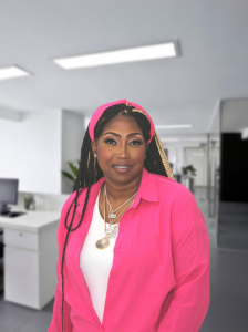 A woman wearing a pink suit in a large office.