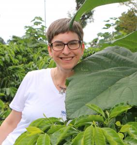 Cathy Key behind the giant leaf of an empress splendor tree
