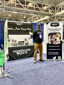Tall man standing in the Homescape Pets exhibit booth at Animal Care Expo 2023 in New Orleans