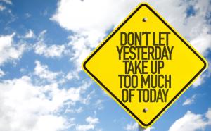 Yellow triangular sign with black letters: Don't let yesterday take up too much of today