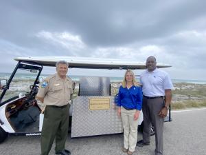 Florida State Parks staff joins Florida Power & Light staff to unveil a new tram at Henderson Beach State Park.